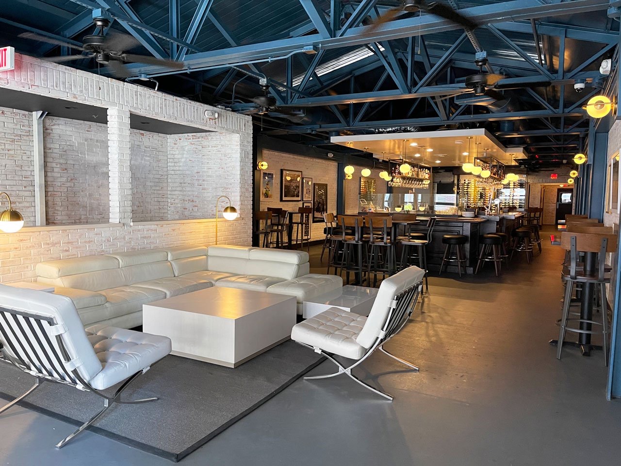 White lounge chairs beneath an exposed steel ceiling at Pa’La