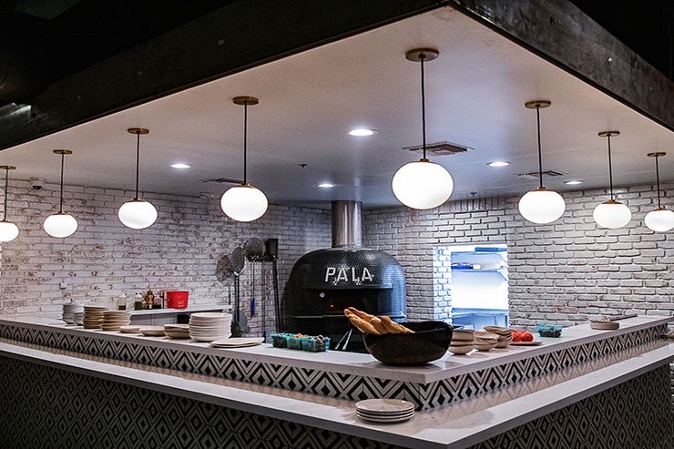 Wood-fired kitchen counter under globe pendants at Pa’La